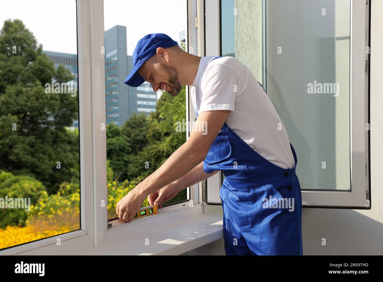 Worker using bubble level after plastic window installation indoors Stock Photo