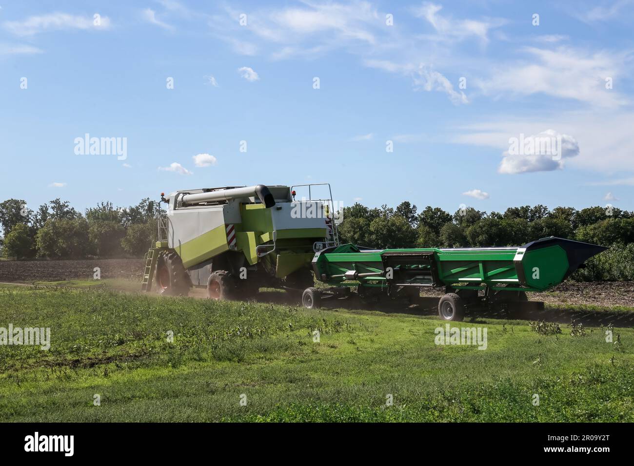 Modern combine harvester with header near agricultural filed Stock Photo