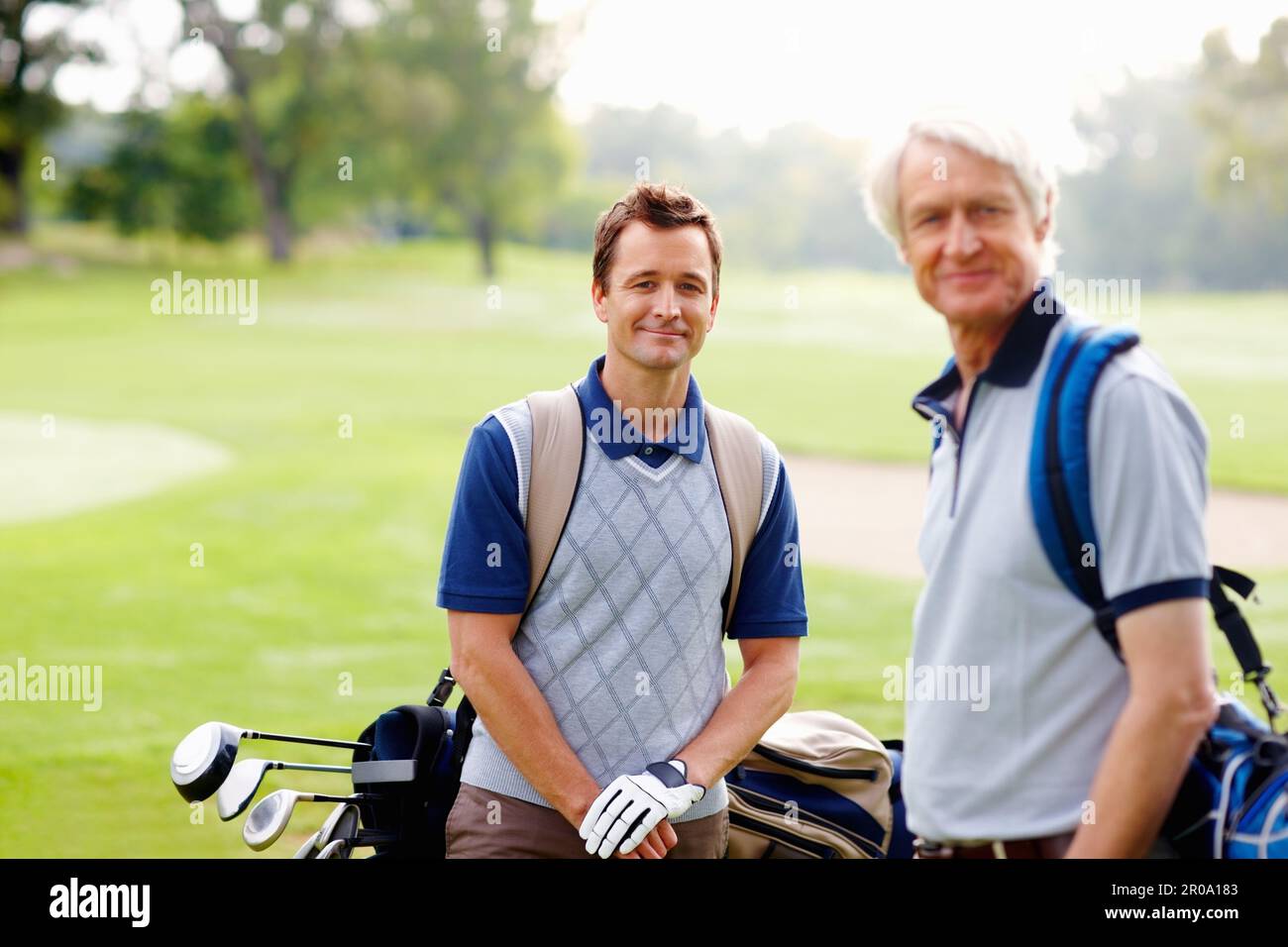 Golfers smiling. Portrait of father and son standing on golf course and giving you an attractive smile. Stock Photo