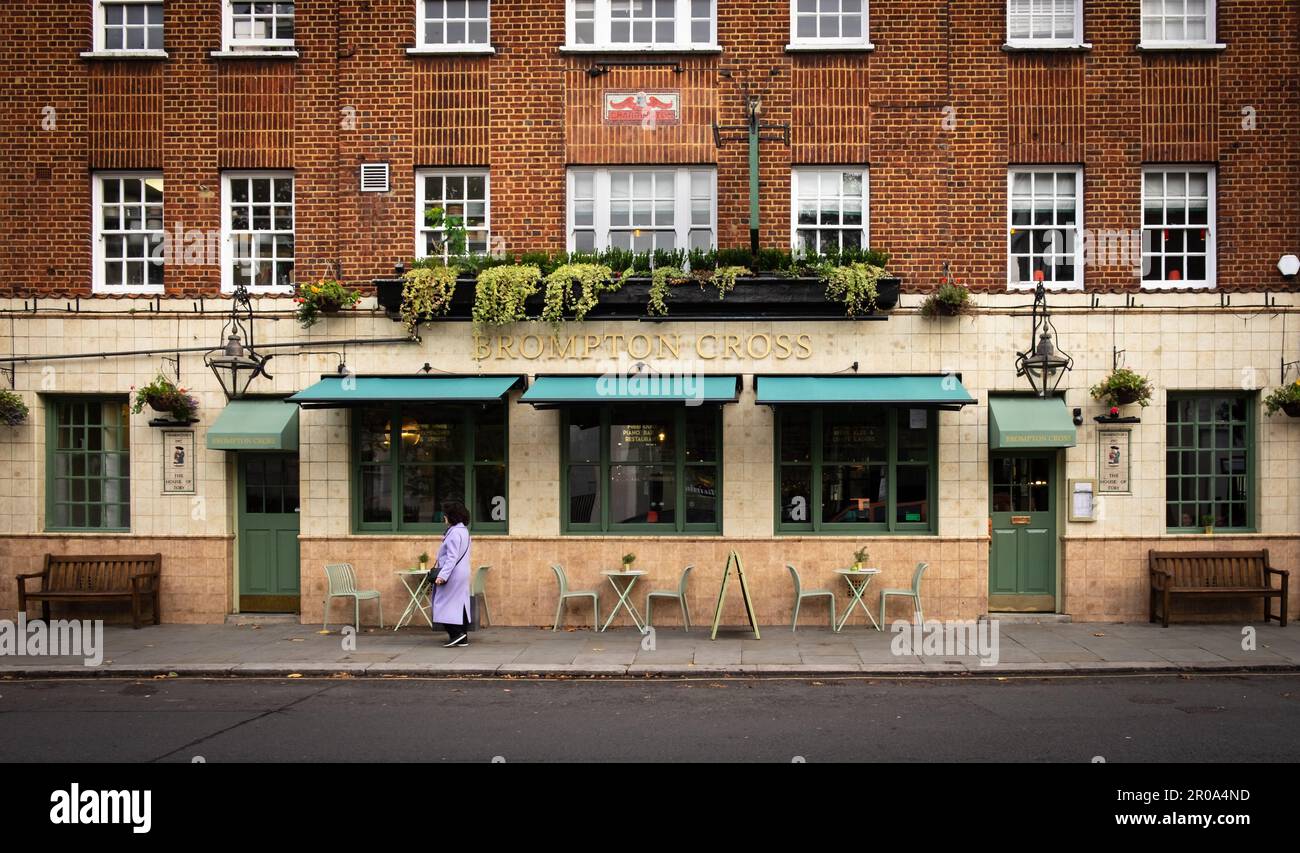 London, UK, Nov 2022, view of a woman walking by the Brompton Cross, a pub and restaurant in the Royal Borough of Kensington and Chelsea Stock Photo