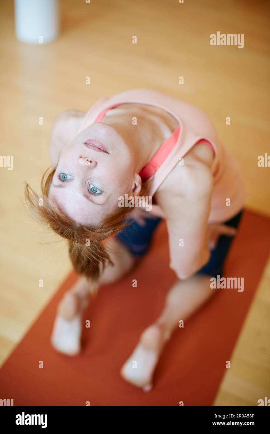 Practicing her backbends. a woman doing a backbend during a yoga workout. Stock Photo