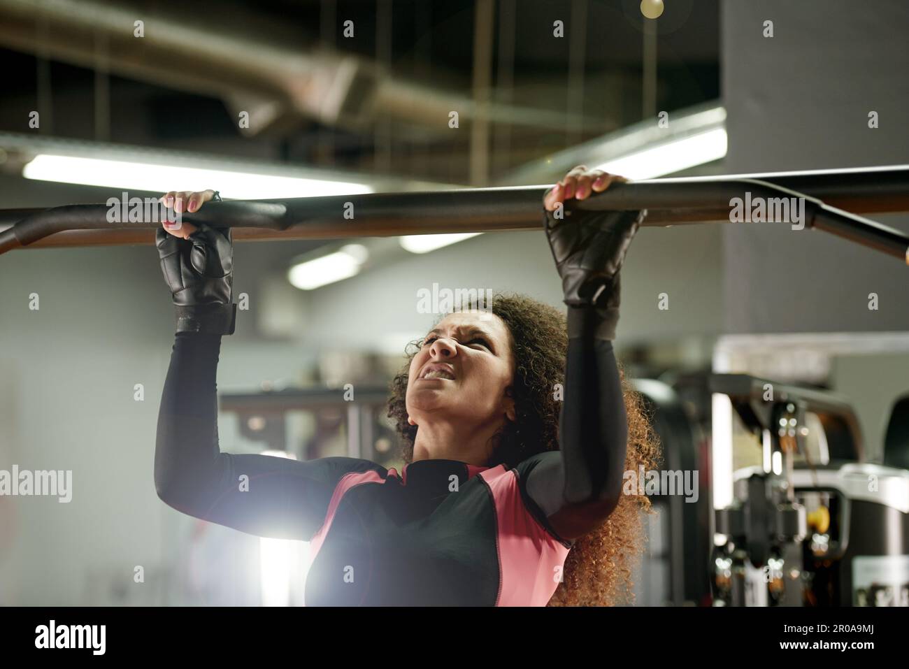 Owning her workout. a young woman doing pull ups at the gym. Stock Photo