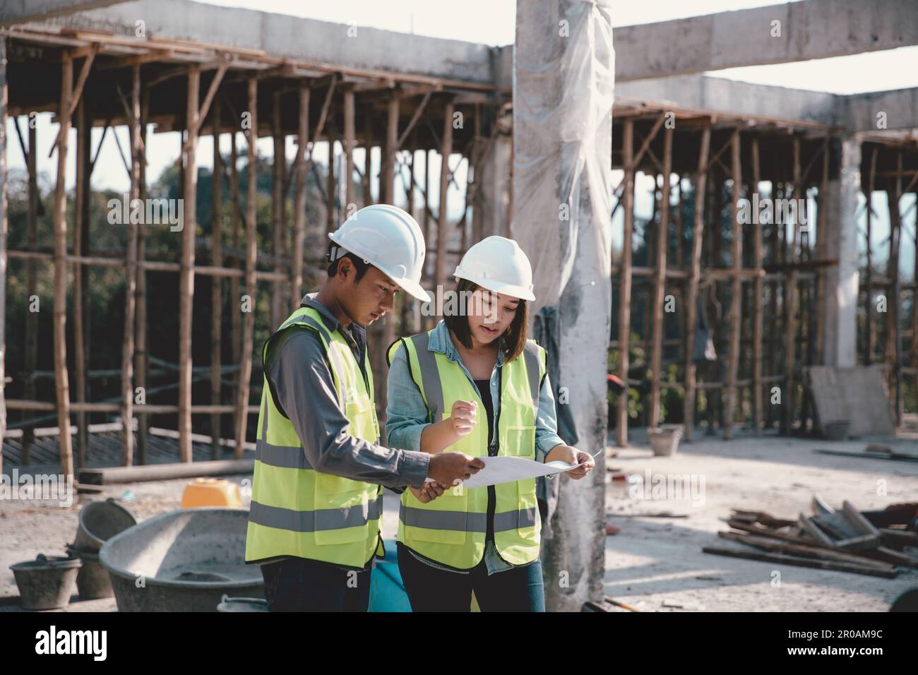 Two specialists inspect commercial, Industrial building construction site. Real estate project with civil engineer, designing commercial buildings on Stock Photo