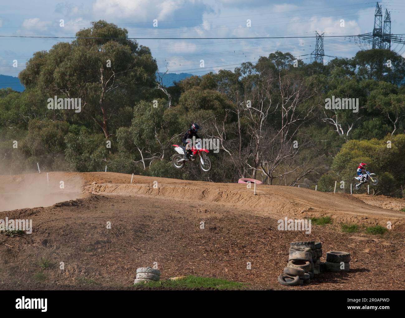 Teenaged motorcycle enthusiasts racing around a motocross racetrack in