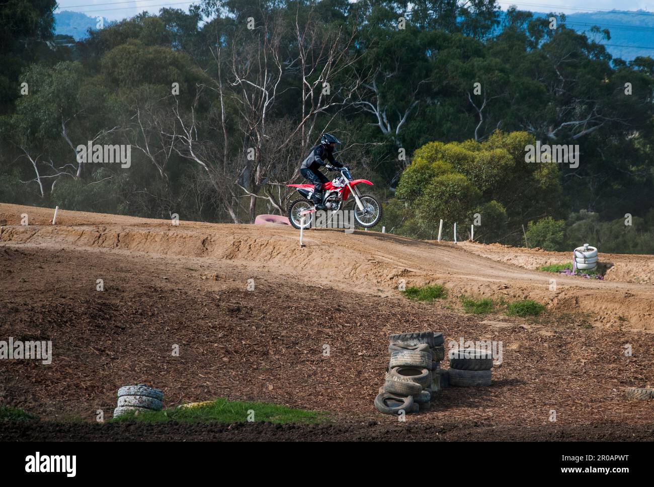 Teenaged motorcycle enthusiasts racing around a motocross racetrack in