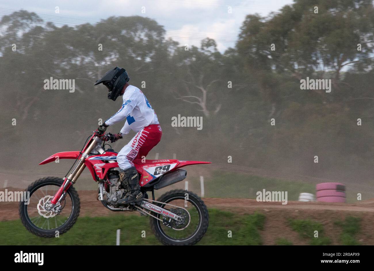 Teenaged motorcycle enthusiasts racing around a motocross racetrack in
