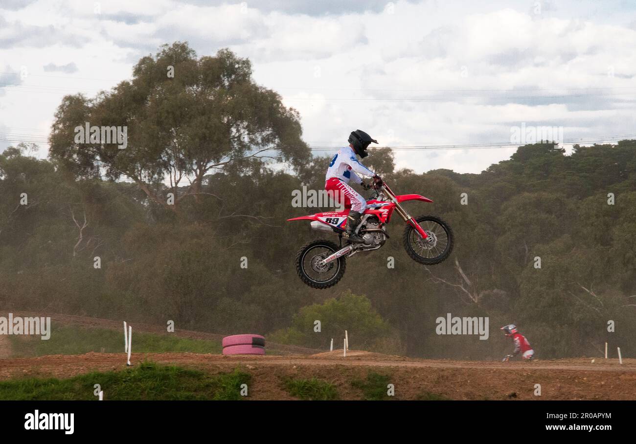 Teenaged motorcycle enthusiasts racing around a motocross racetrack in