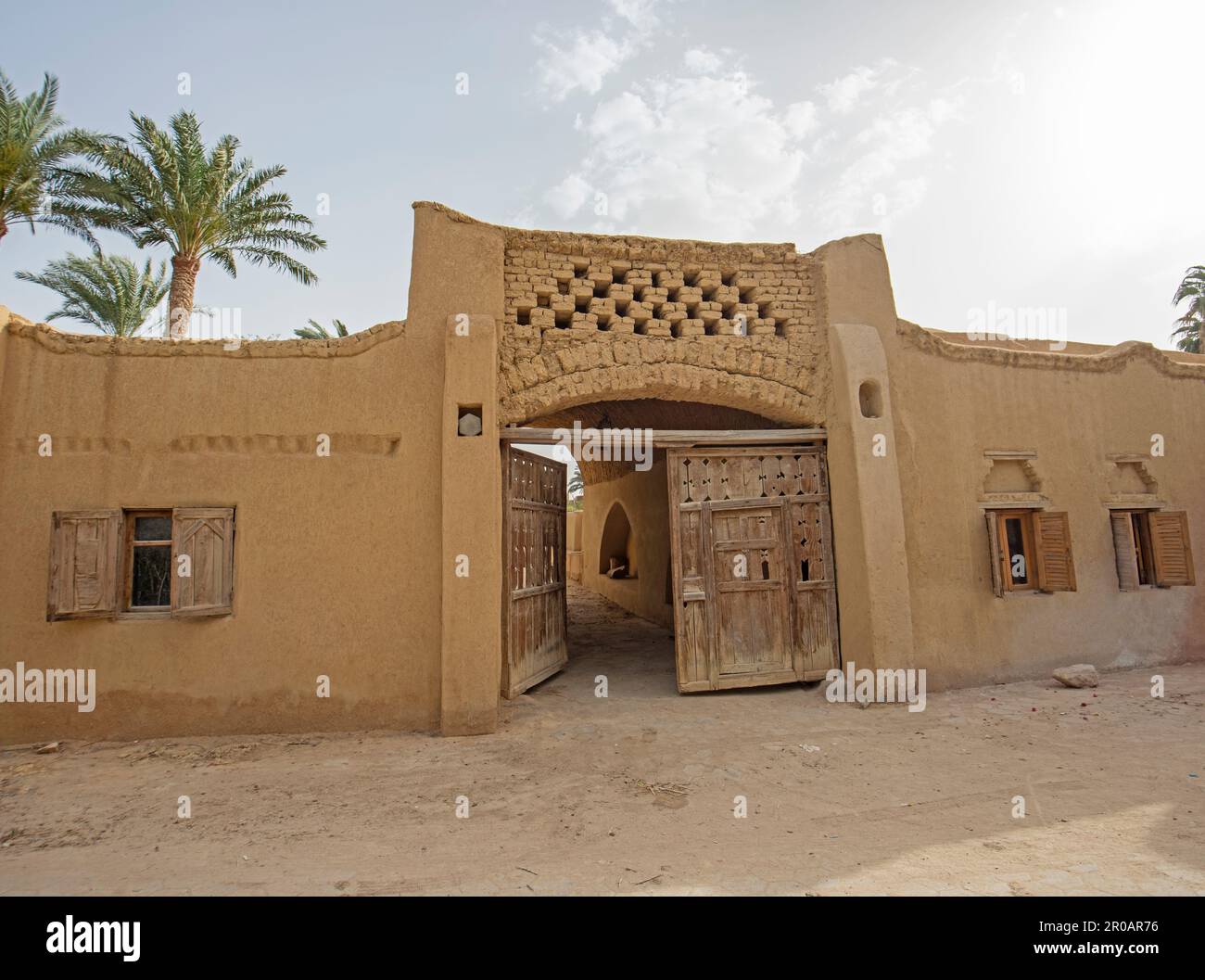 Old rustic wooden door entrance gate in wall of traditional mud brick egyptian house Stock Photo