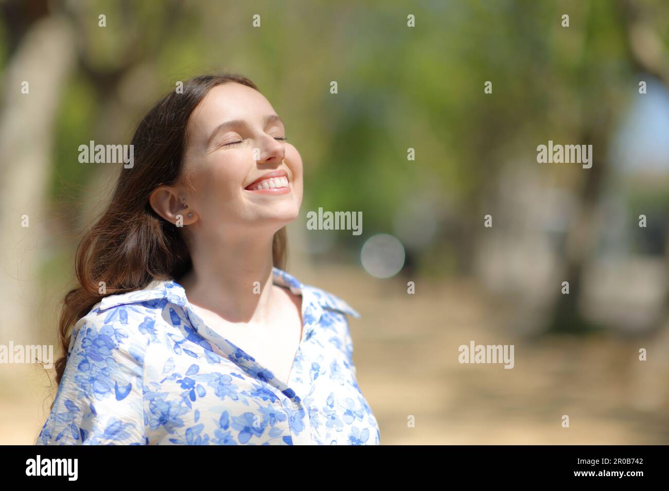 Happy woman breathing fresh air standing alone in a park Stock Photo ...