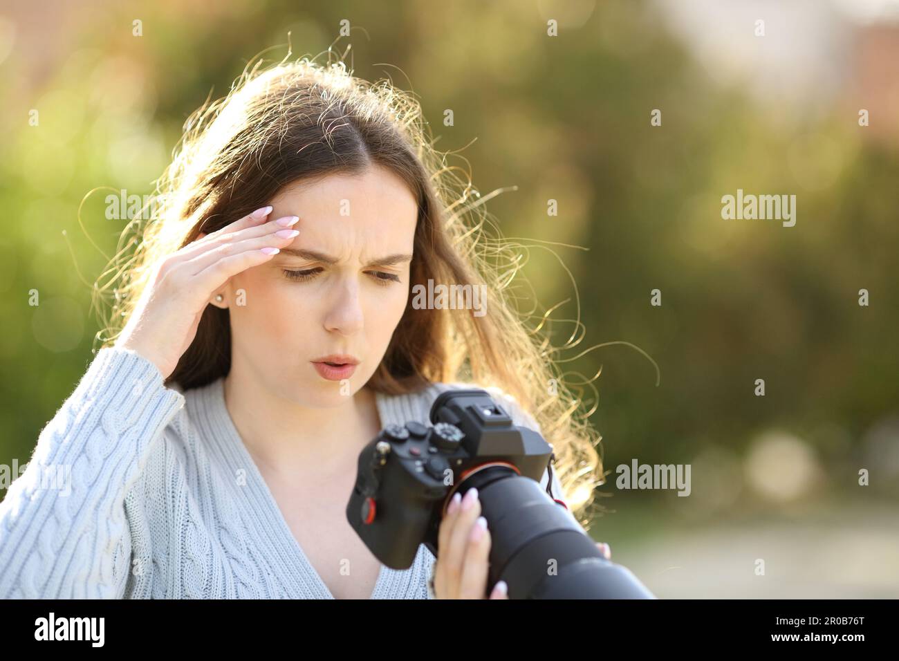 Worried photographer checking bad photos on mirrorless camera in a park Stock Photo