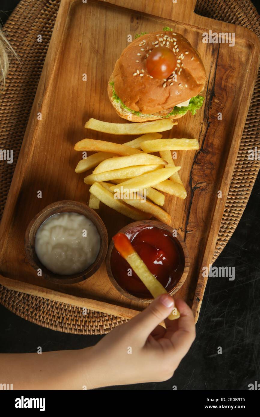 Little girl eating french fries with tomato sauce at the restaurant Stock Photo
