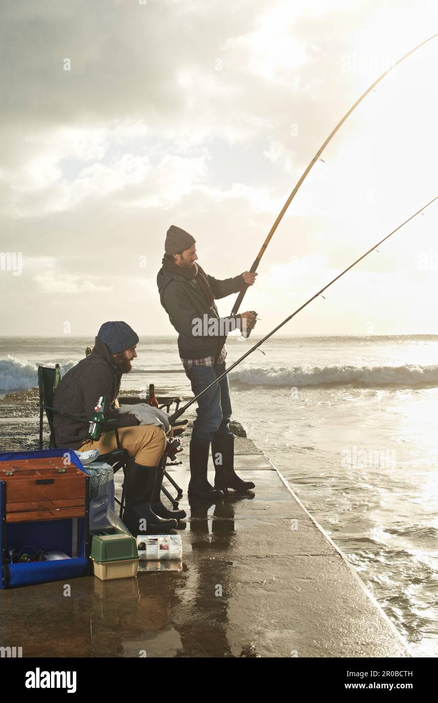 Doing a little fishing. two young men fishing off a pier. Stock Photo