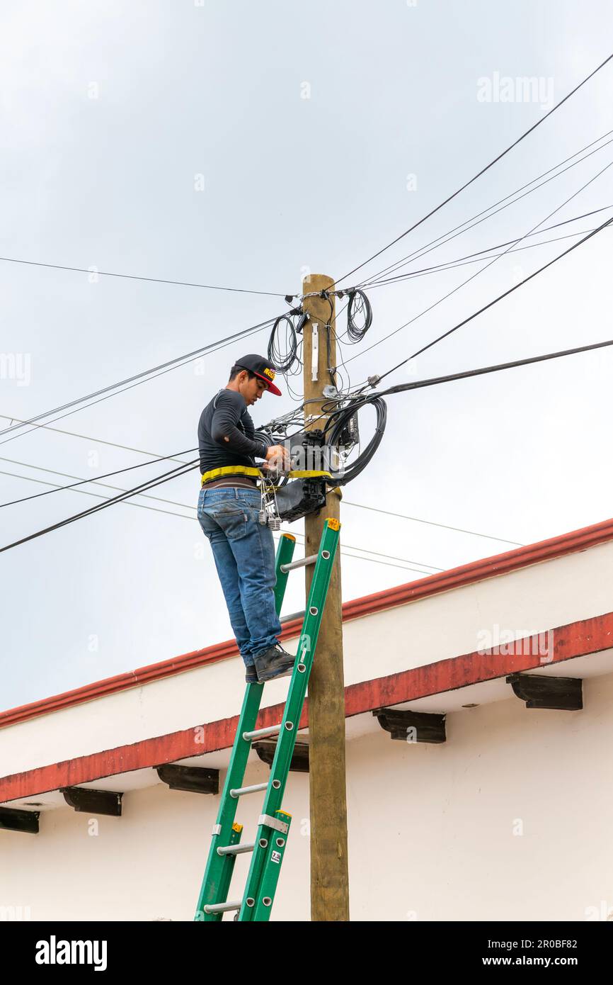 Electrician on ladder working on electricity power lines, Bacalar
