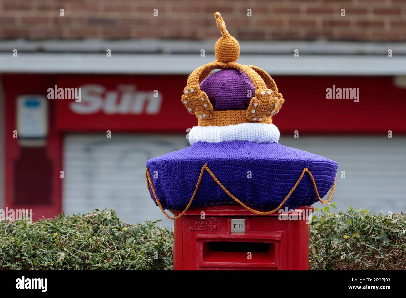 King charles111 coronation celebrations may 2003 Horsham w.sussex uk gold crown knitted decoration on red post box purple white and yellowish gold Stock Photo