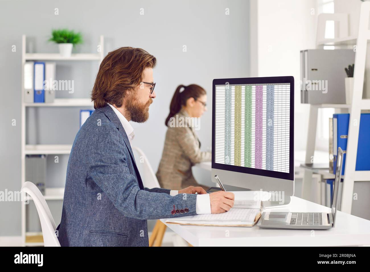 Male accountant in office working using accounting report spreadsheet on computer screen. Stock Photo