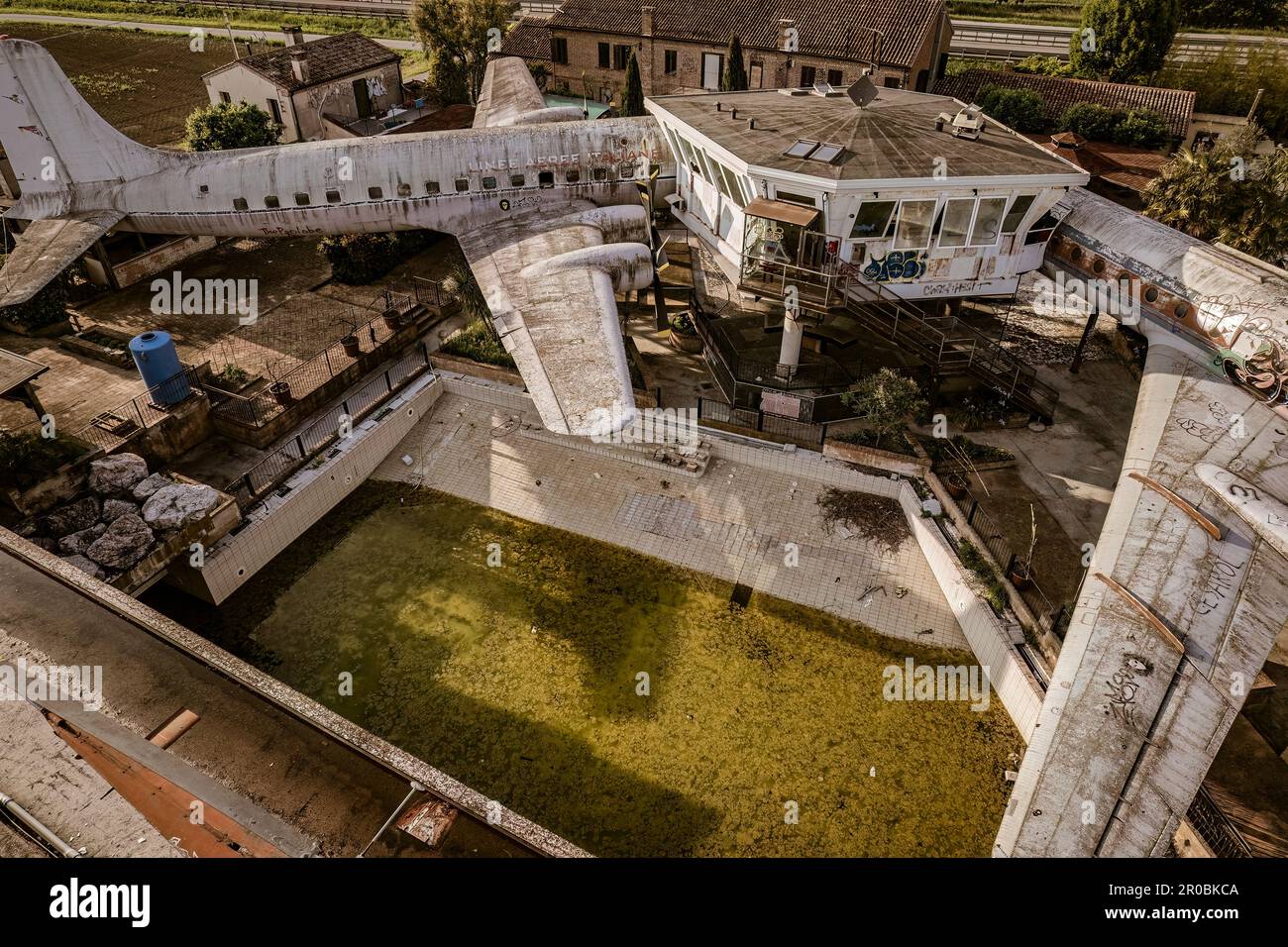 An eerie view of abandoned airplanes scattered near a control tower in a deserted aviation site. Stock Photo