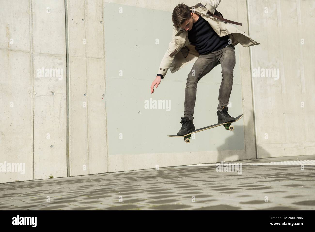 Young man jumping with skateboard in mid-air, Munich, Bavaria, Germany Stock Photo