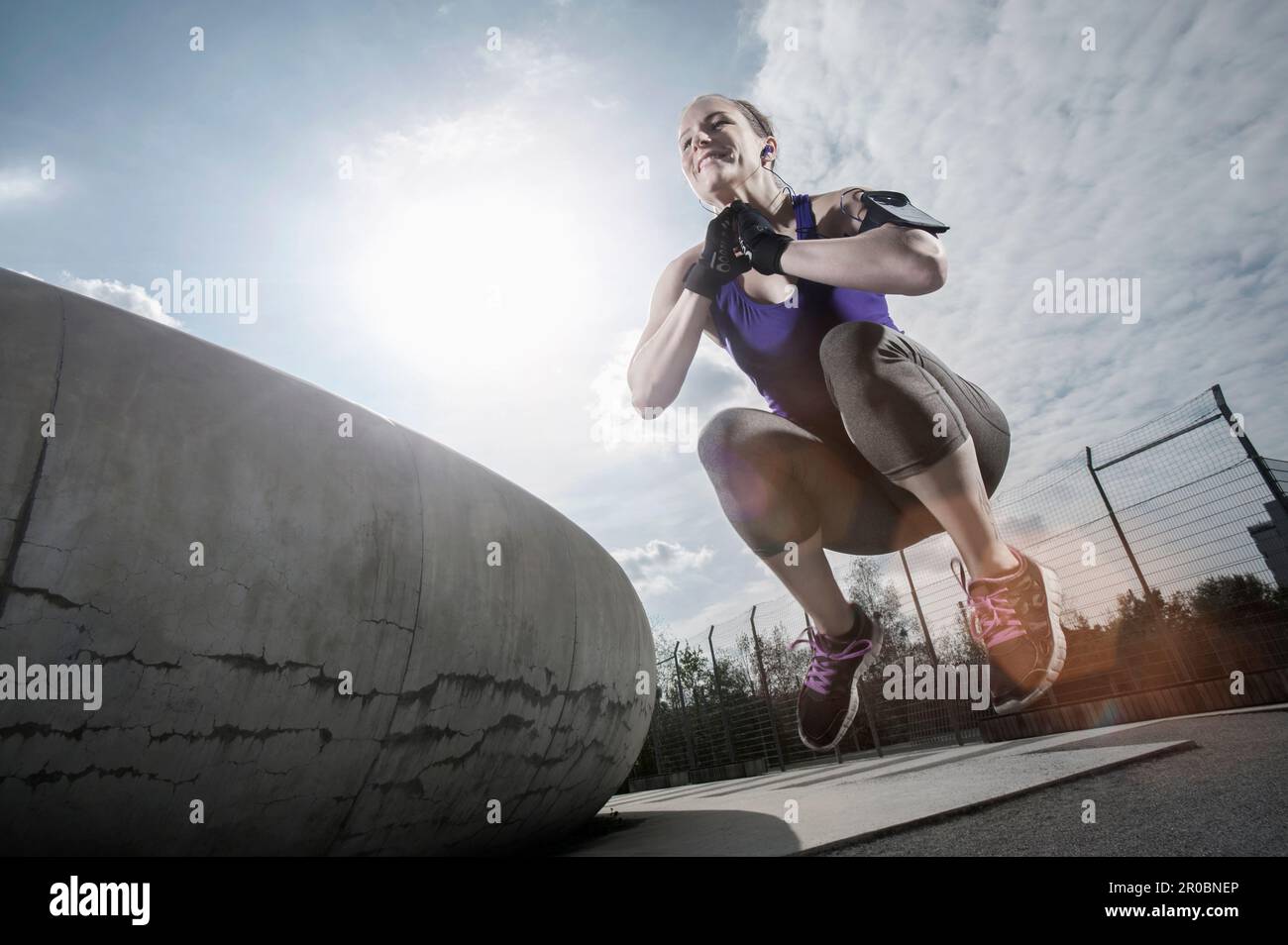 Young woman jumping in mid-air and listening to music, Bavaria, Germany Stock Photo