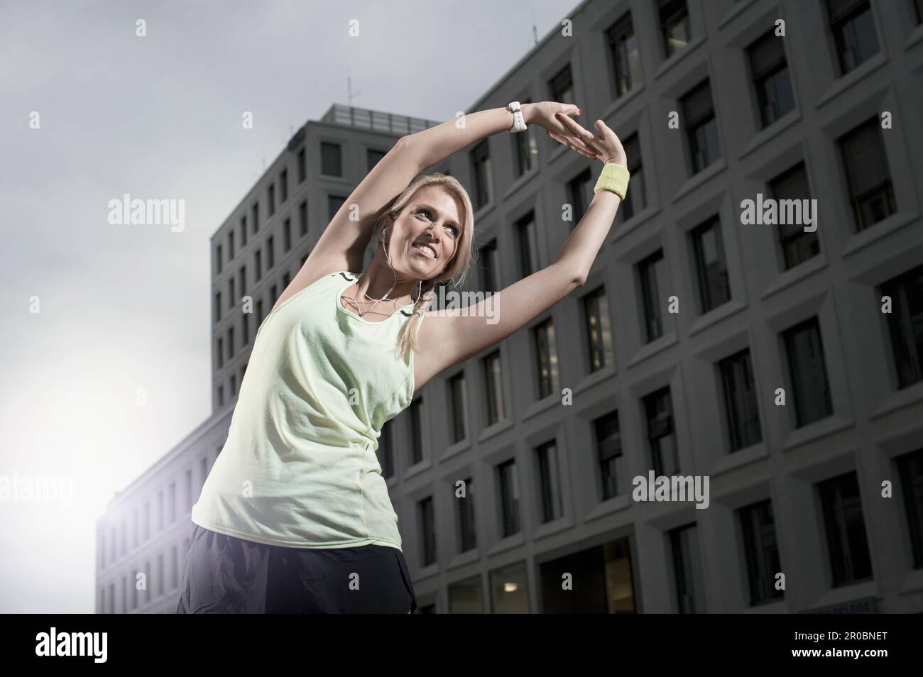Mid adult woman stretching her body and listening to music, Bavaria, Germany Stock Photo