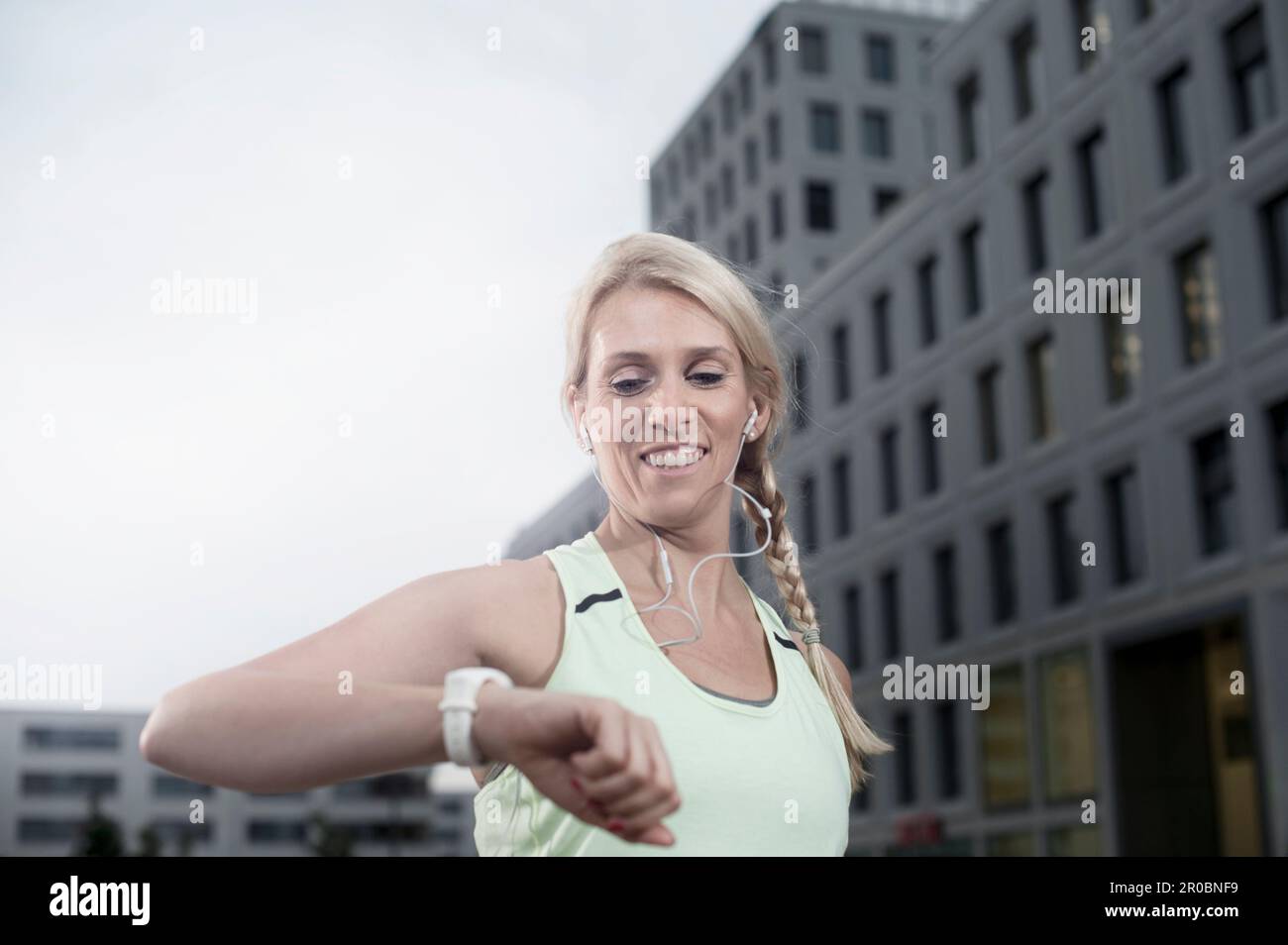 Mid adult woman checking the time after exercising and listening to music, Bavaria, Germany Stock Photo