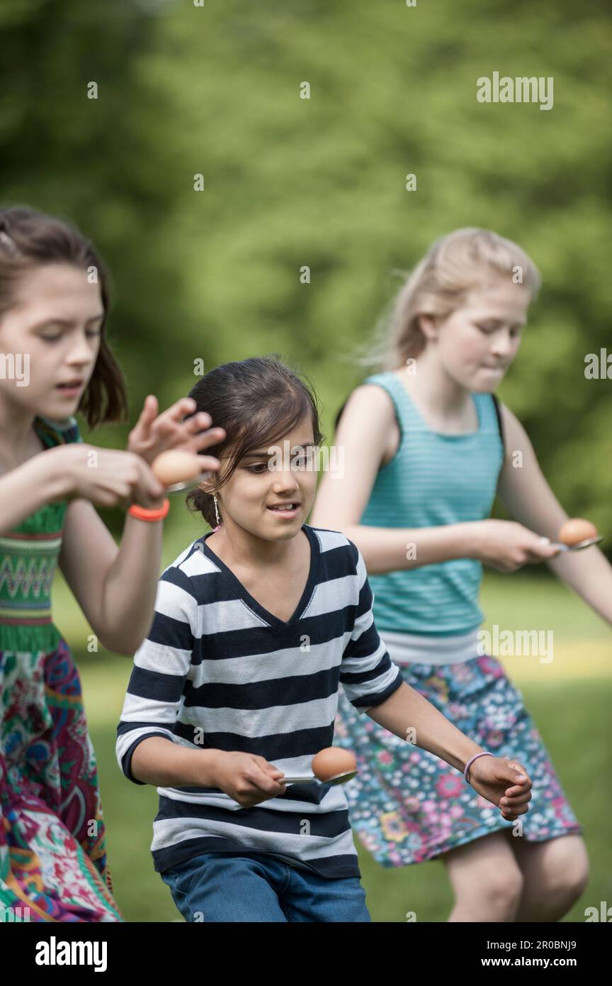 Group of girls competing in an egg-and-spoon race in a park, Munich, Bavaria, Germany Stock Photo