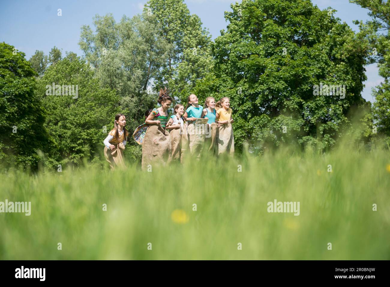 Group of girls playing in sack race on a field, Munich, Bavaria, Germany Stock Photo