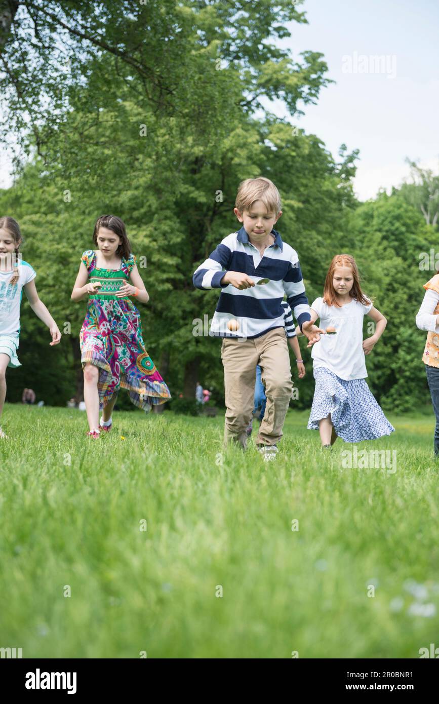 Group of children competing in an egg-and-spoon race in a park, Munich, Bavaria, Germany Stock Photo