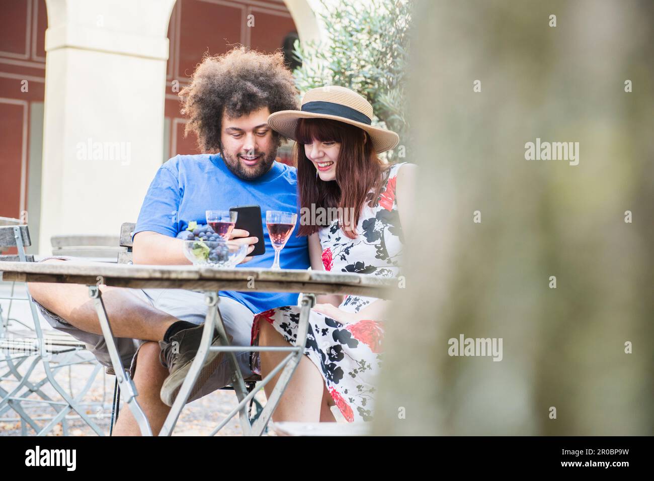 Young couple using mobile phone at outdoor restaurant Stock Photo