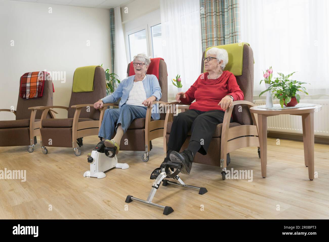 Two senior women doing exercise on mini foot pedal exerciser in rest
