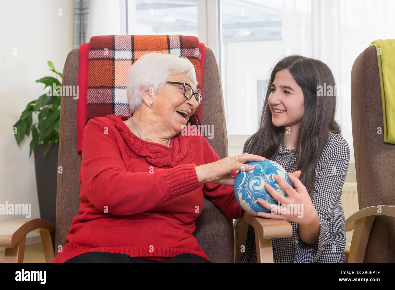Girl playing bowling with senior woman in rest home Stock Photo