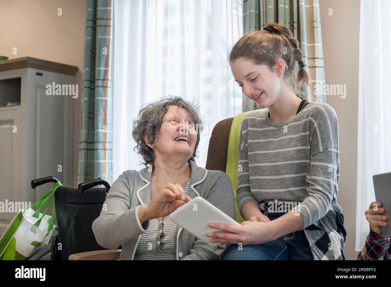 Senior women with granddaughter using digital tablet in rest home Stock Photo