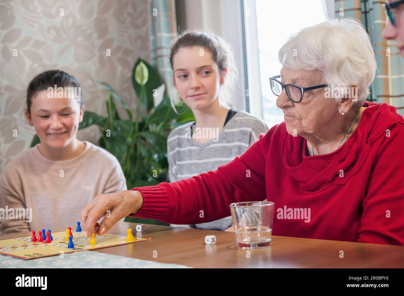 Girls playing ludo board game with senior women in rest home Stock Photo