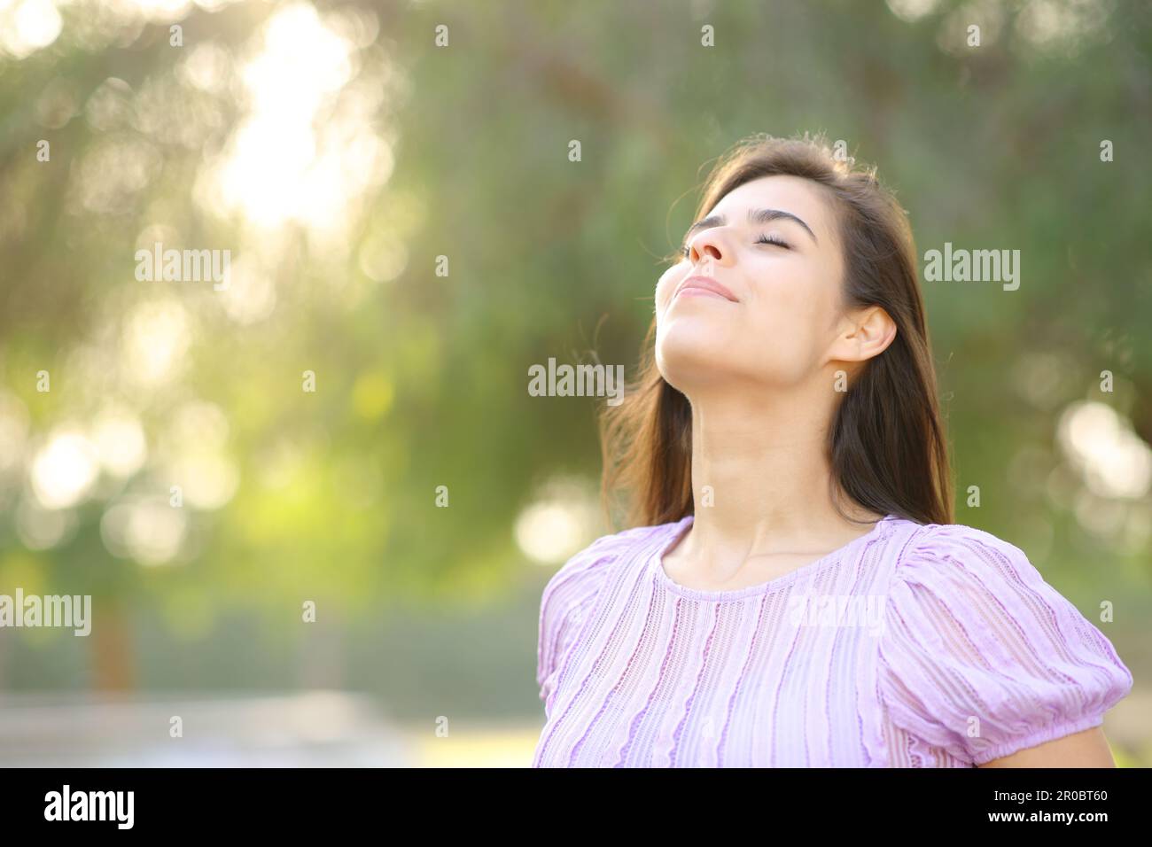 Satisfied woman breathing fresh air in a park standing alone Stock Photo