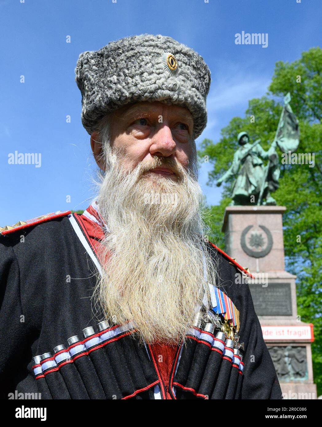 Dresden, Germany. 08th May, 2023. 08 May 2023, Saxony, Dresden: A participant in Cossack uniform takes part in a commemoration of Liberation Day at the Red Army Memorial with the inscription 'This structure is fragile'. The occasion for the Temporary Art Installation at the Soviet Memorial at Olbrichtplatz in Dresden's Albertstadt in cooperation with the Kunsthaus Dresden and the artist Svea Duwe is here not only the liberation from National Socialism and the upcoming renovation of the memorial, but also the historical classification of the memorial required by the Russian war of aggression on Stock Photo