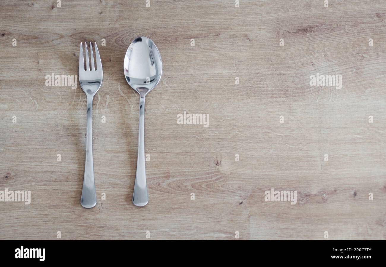 A top down view on a cutlery in wooden background. dining accessories. spoon and fork Stock Photo