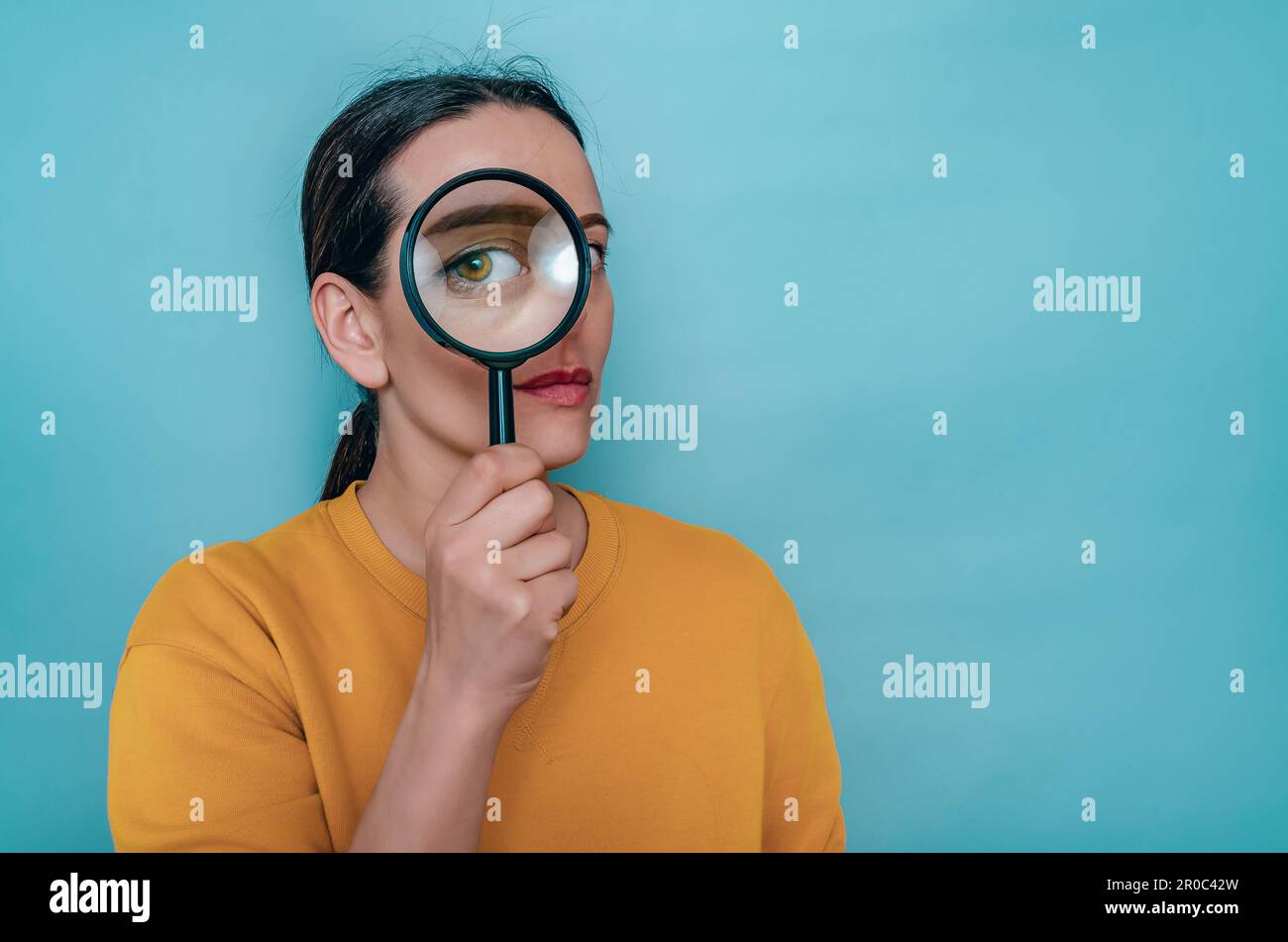 Magnifying glass. Woman's face through magnifying glass. Big eyes. Research, choice concept