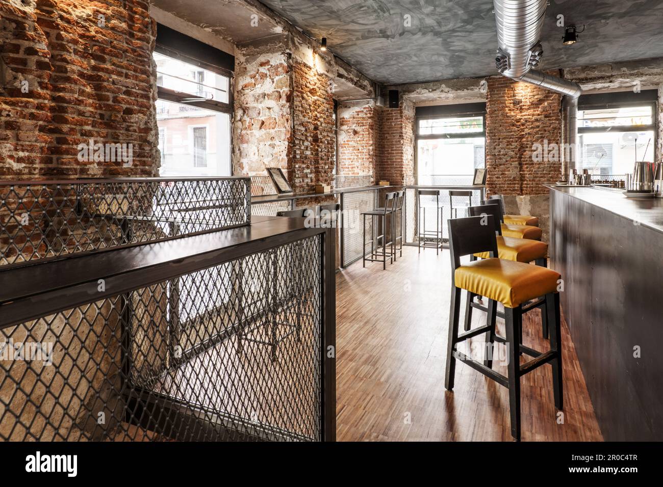 A local bar counter with tall armchairs with yellow seats, industrial