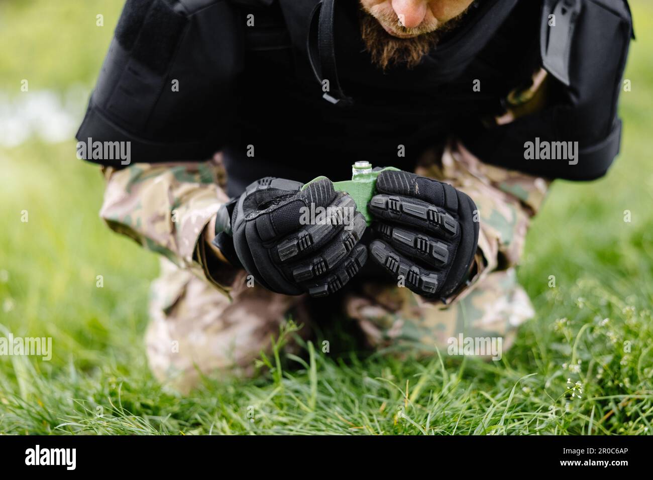 A man in a special suit works with a detector and found an explosive device. A man tries to neutralize high-explosive anti-personnel pressure mine. Stock Photo