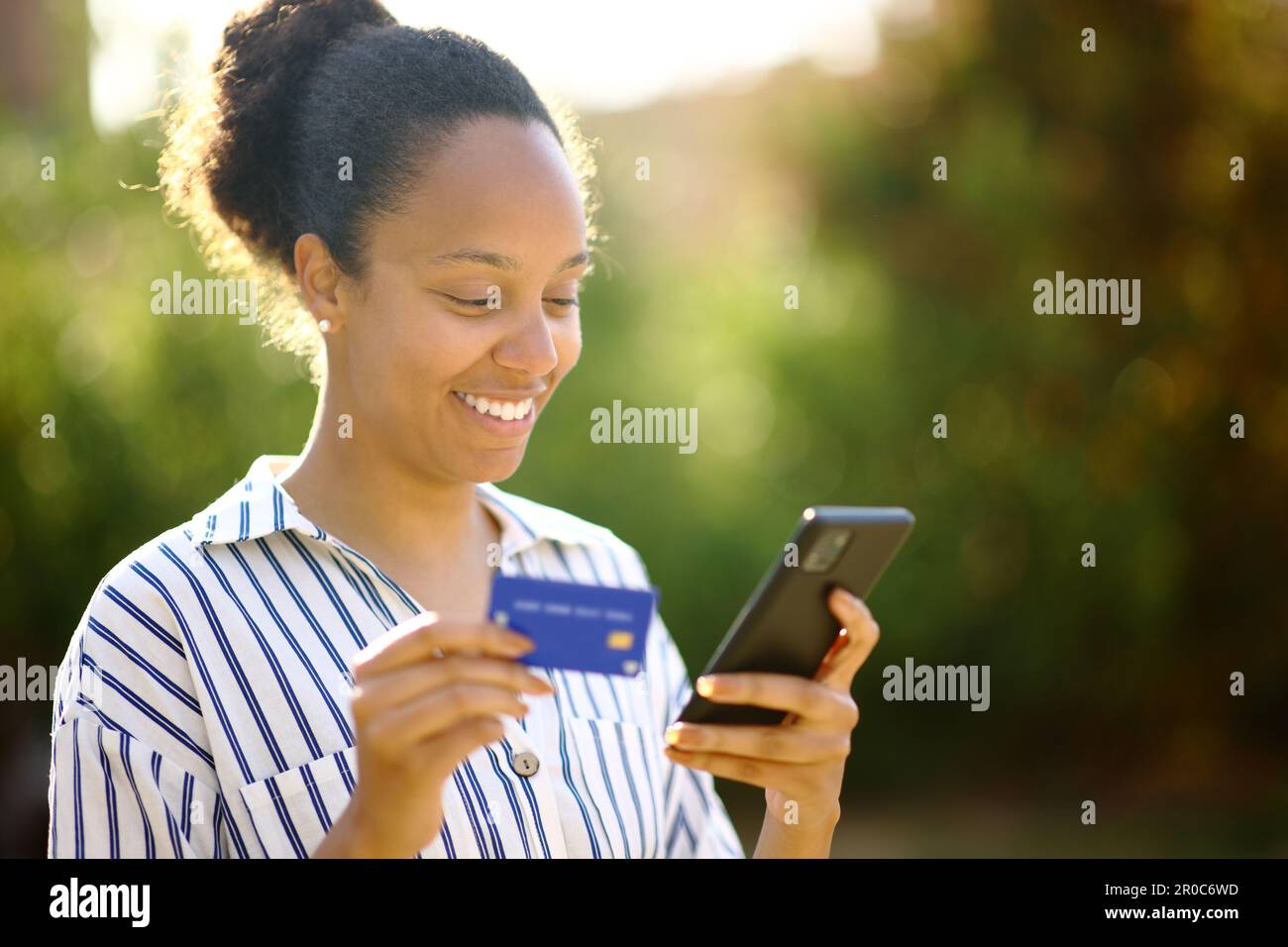 Black woman buying online with credit card and smart phone in a park Stock Photo