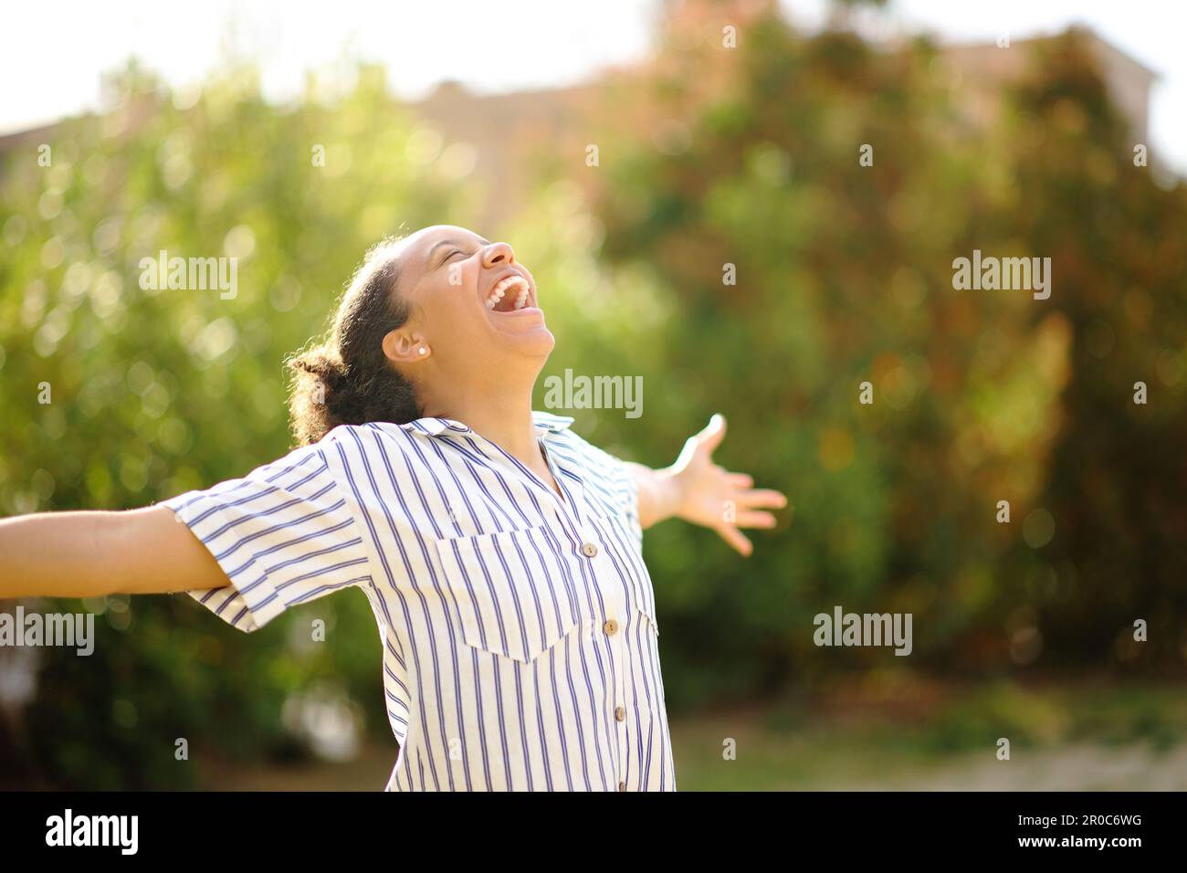 Excited black woman spreading and screaming in a park Stock Photo
