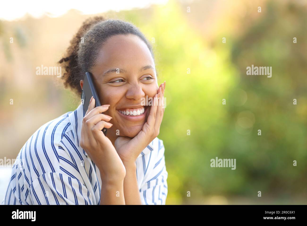 Happy candid black woman calling on phone in a park Stock Photo