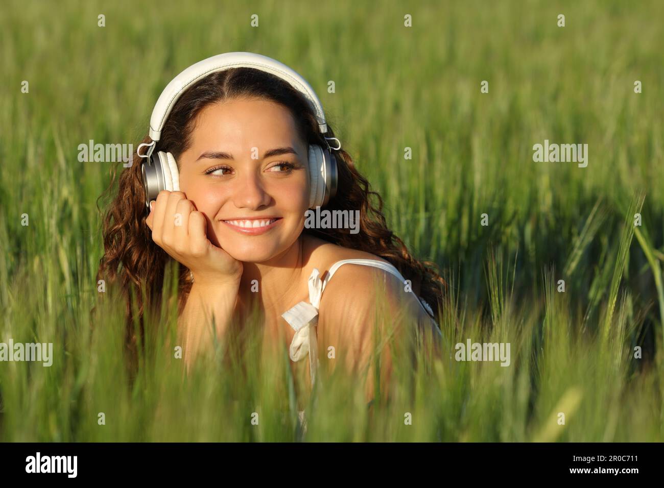 Happy woman listening to music in a green field looking at side Stock Photo