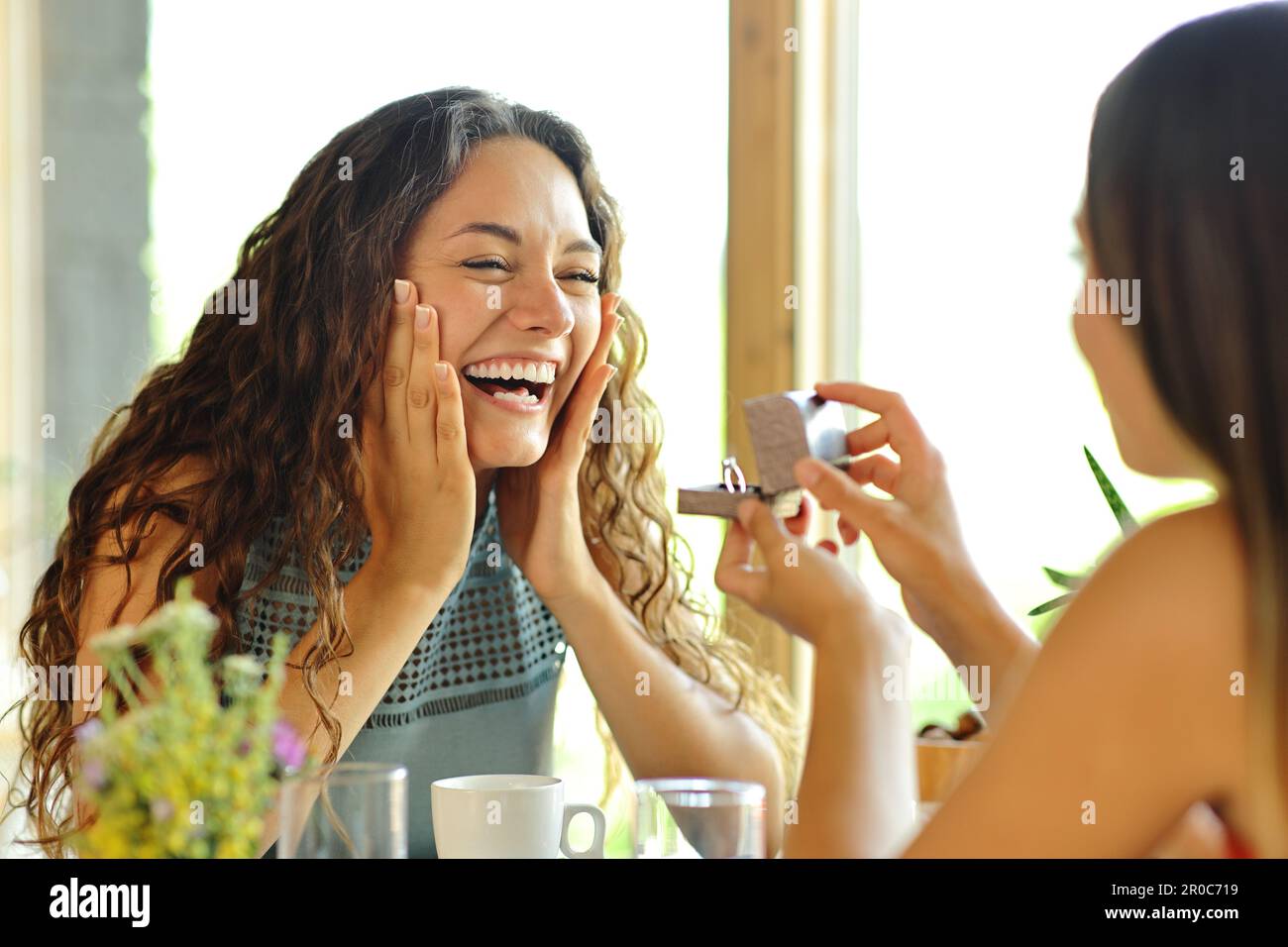 Happy lesbian couple asking for marriage in a restaurant Stock Photo