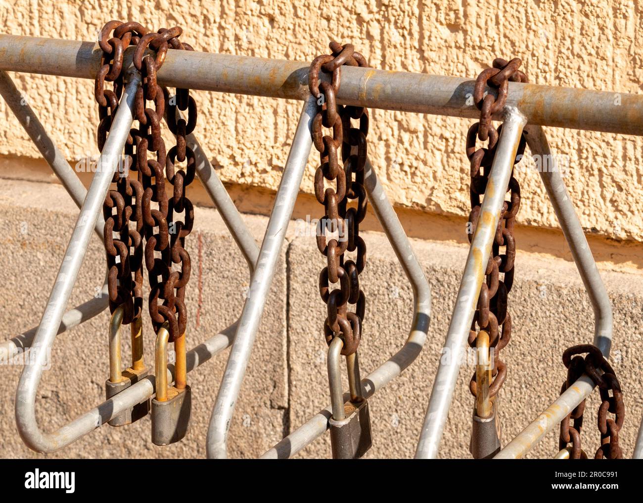 Rusty heavy padlocks and chains attached to bike stand rack Stock Photo