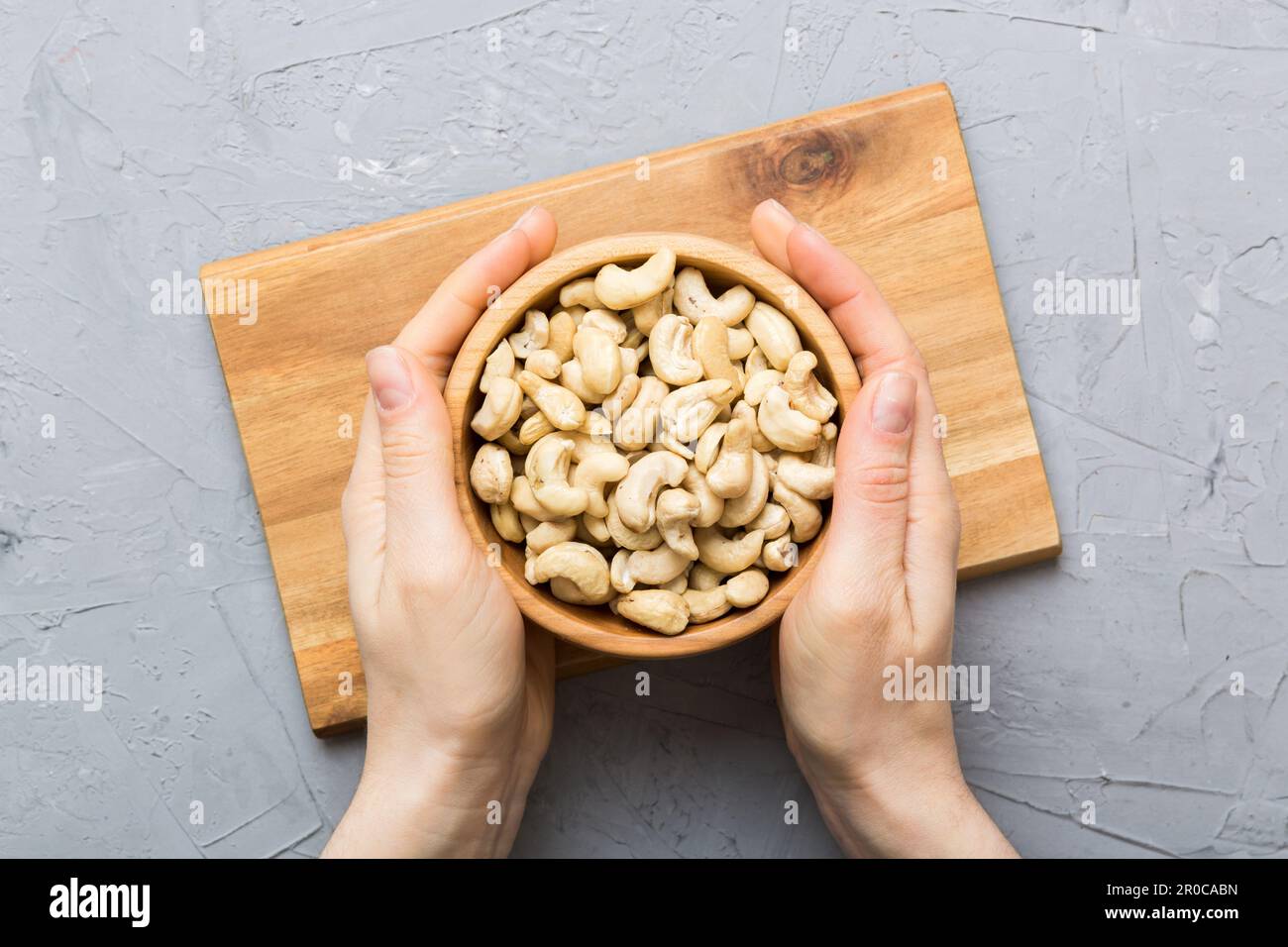 Woman hands holding a wooden bowl with cashew nuts. Healthy food and ...