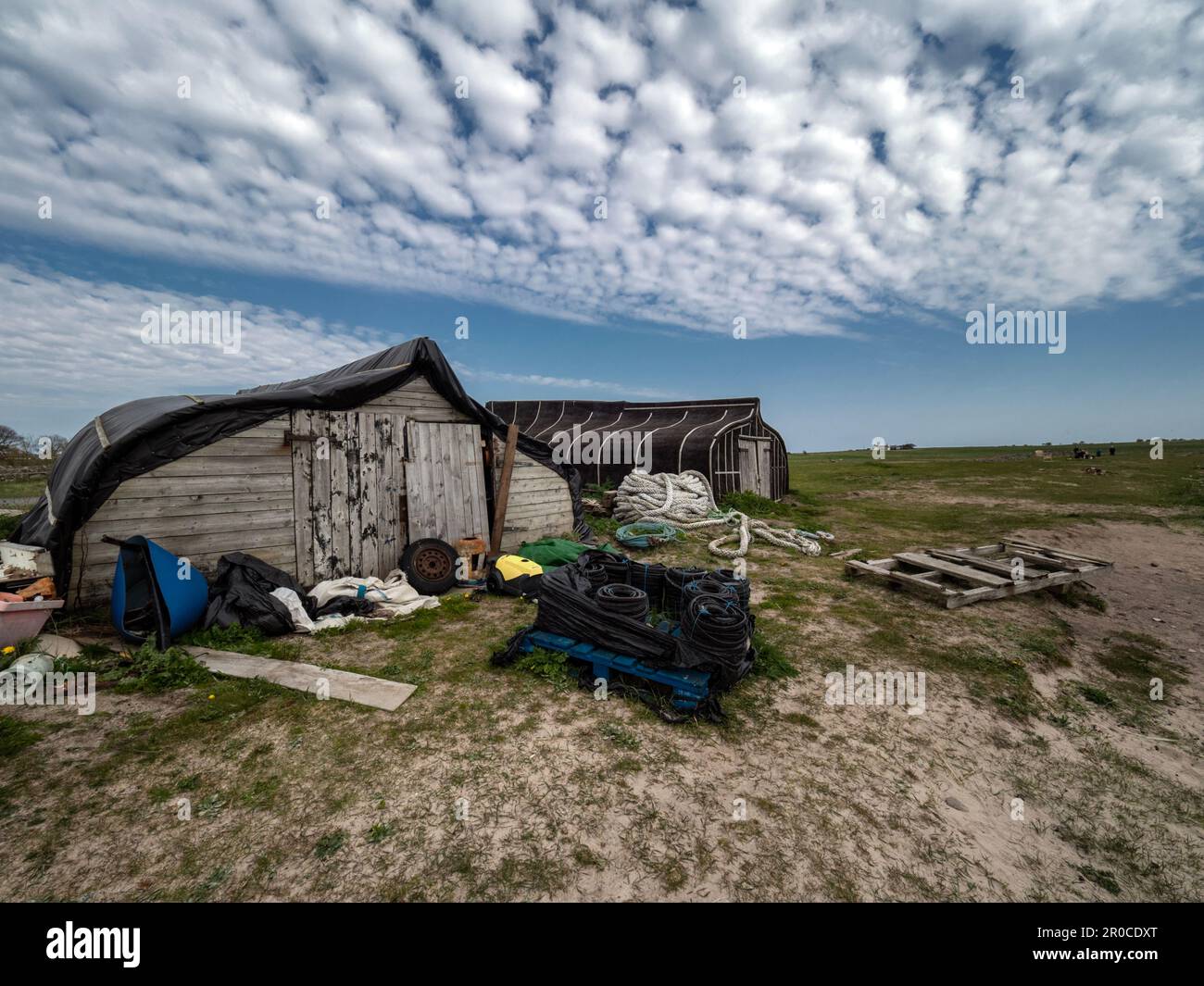 Upturned boats used as store houses on the beach at the Holy Island of Lindisfarne, Northumberland, England, UK Stock Photo