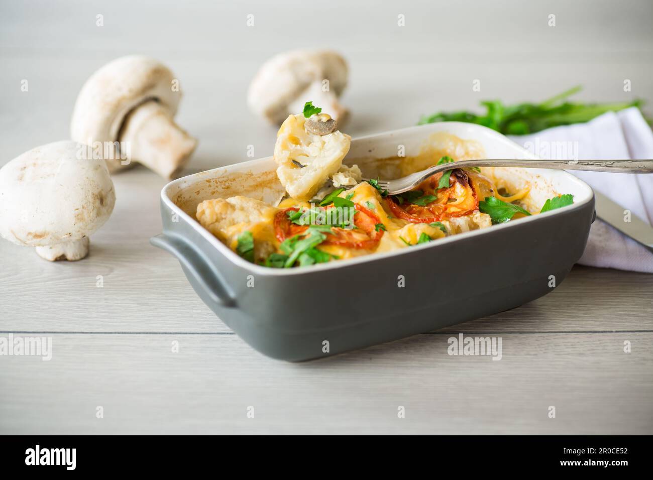 cauliflower baked with chicken fillet and mushrooms under cheese in a ceramic form, on a wooden table. Stock Photo