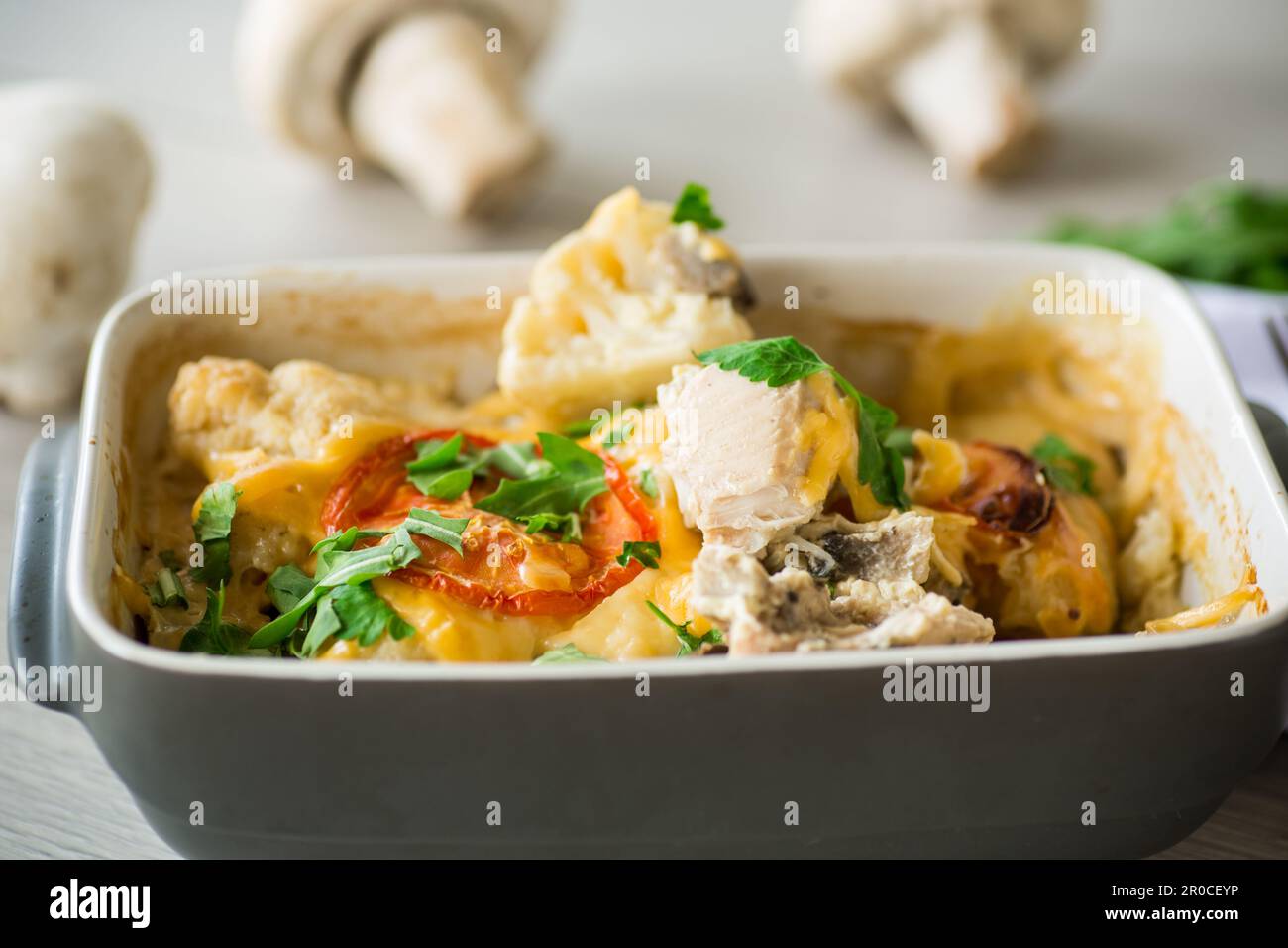 cauliflower baked with chicken fillet and mushrooms under cheese in a ceramic form, on a wooden table. Stock Photo