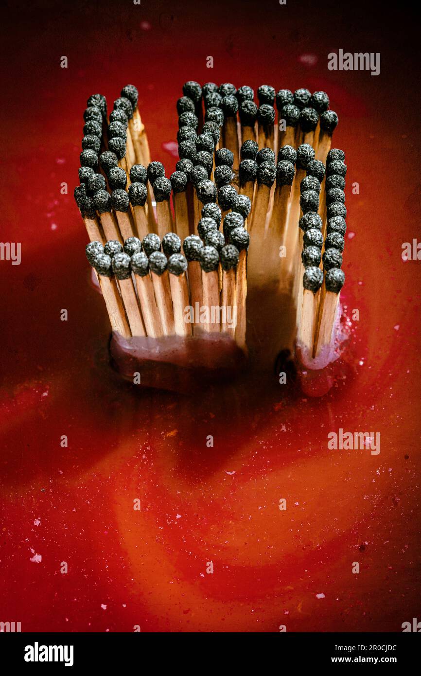 swastika with burnt matches in sea of blood background Stock Photo