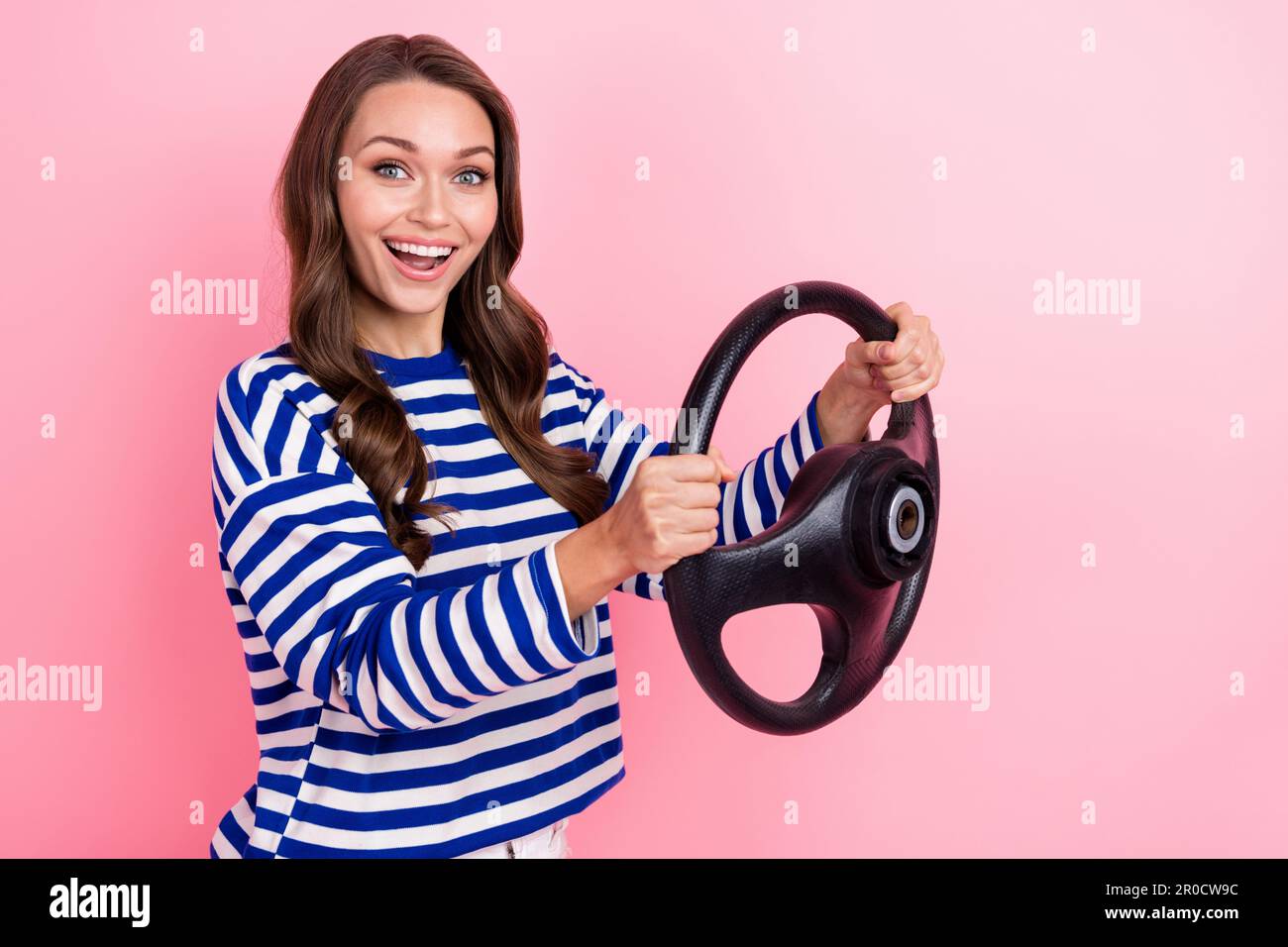 Photo of beautiful young lady wear striped blue shirt hold steering wheel audi new insurance rent cars isolated on pink color background Stock Photo